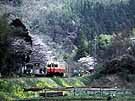 A shingle unit train is making a stop at a small station in rustic scenery